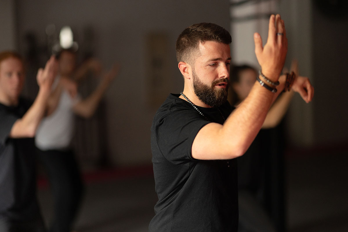 A man performs a martial arts move, showcasing strength and agility in a dynamic pose.
