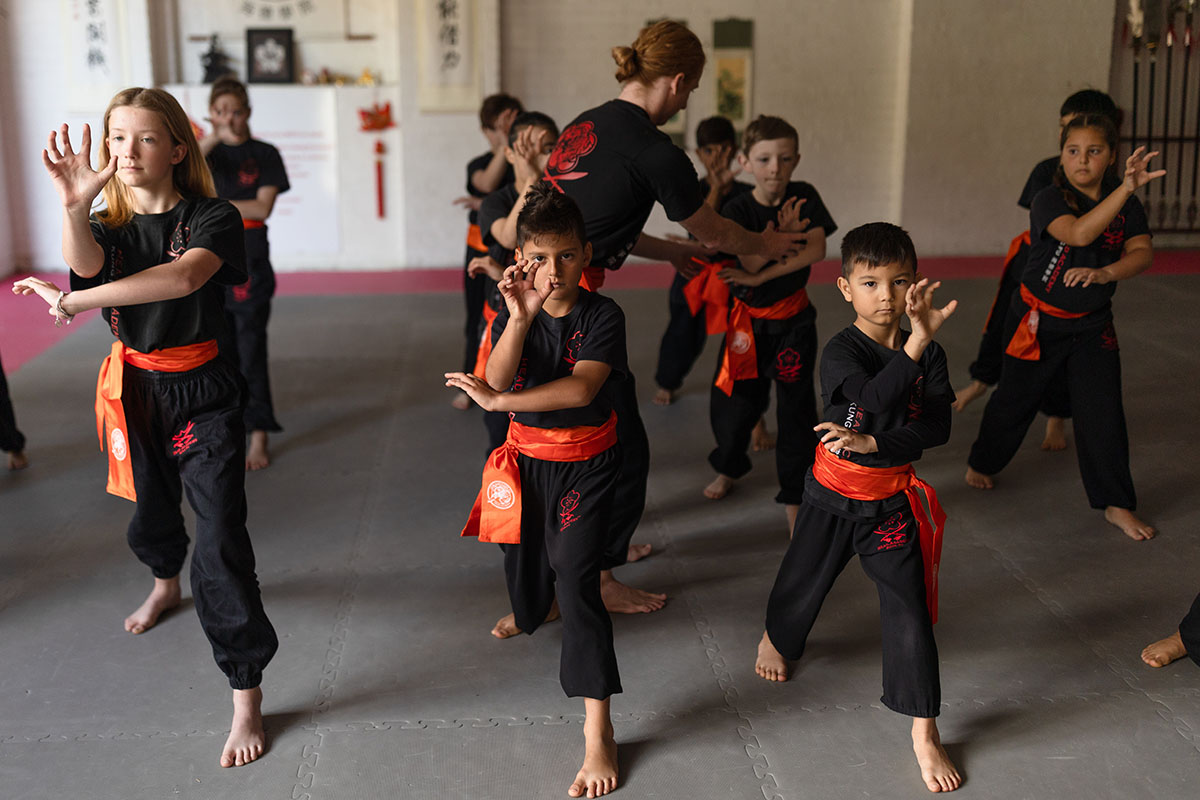 A group of children practicing Jow Gar Kung Fu in a gym, showcasing martial arts techniques and teamwork.